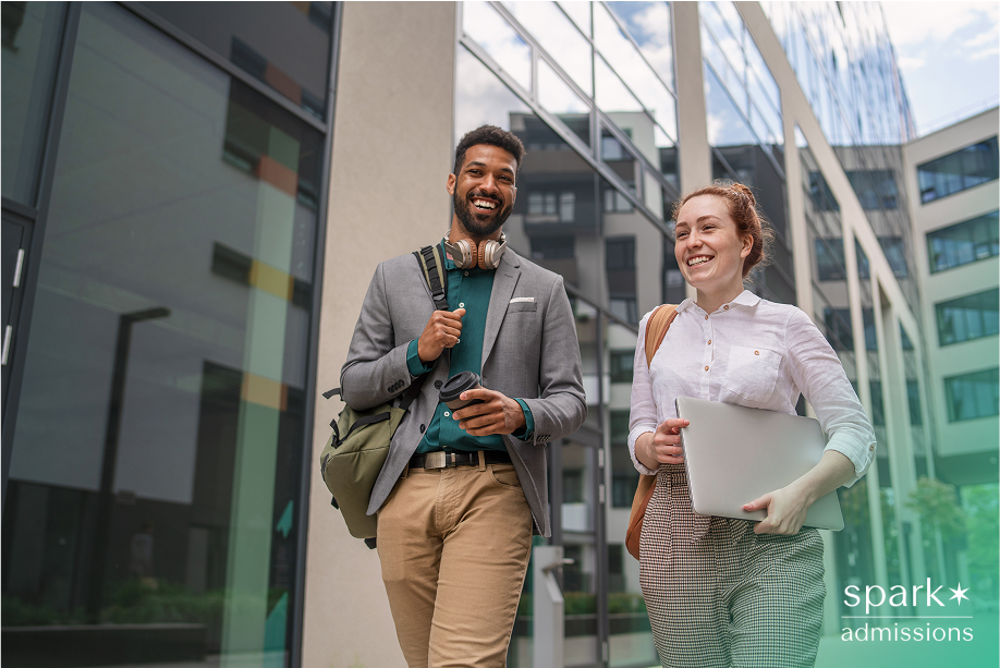Two students smile while walking outside a modern academic building