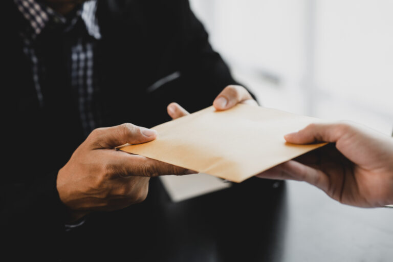 A person hands over a sealed envelope to another person