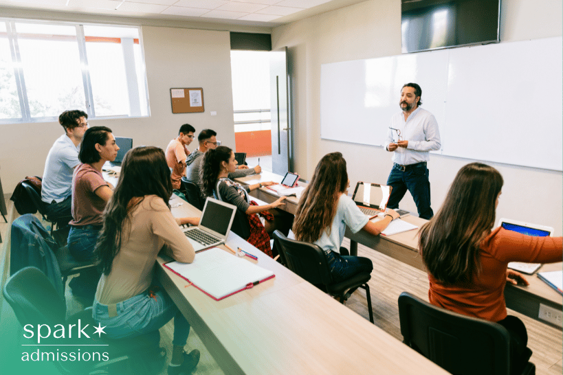 College students in a classroom with laptops listening attentively to a professor