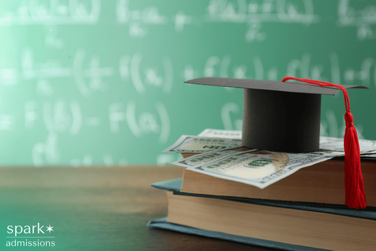 Graduation cap on books with dollar bills representing merit aid