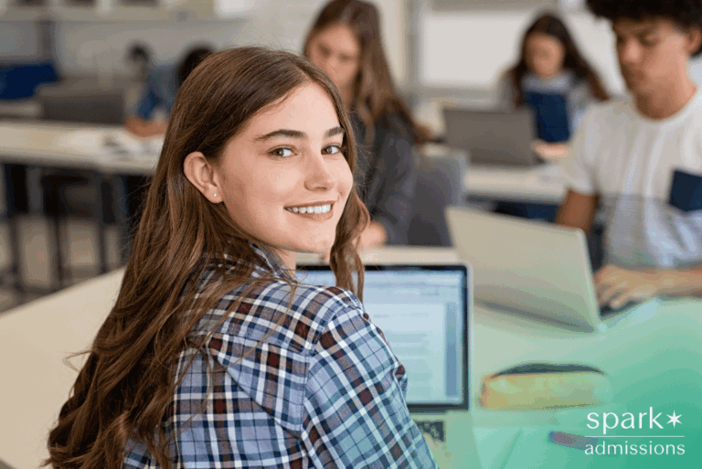 Smiling female student using laptop to complete Common App for college